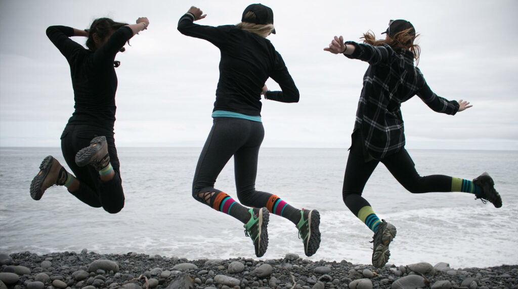 Three people jumping and showing off their colorful Point6 socks.