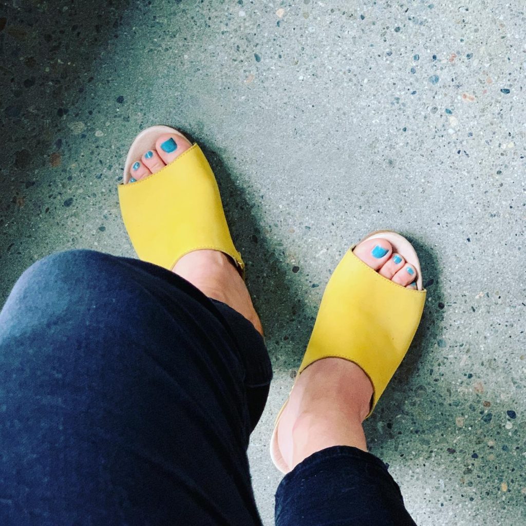 Woman stepping into yellow Dansko shoes. 